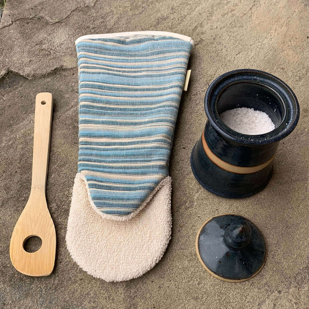 Blue striped long gauntlet style oven glove flat picture with light brown background one cooking wooden spoon and a pot of salt 