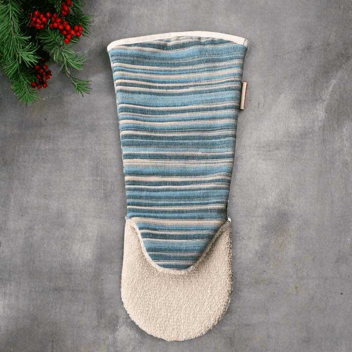 Long oven glove striped blue and beige on grey textured background with christmas decor 
