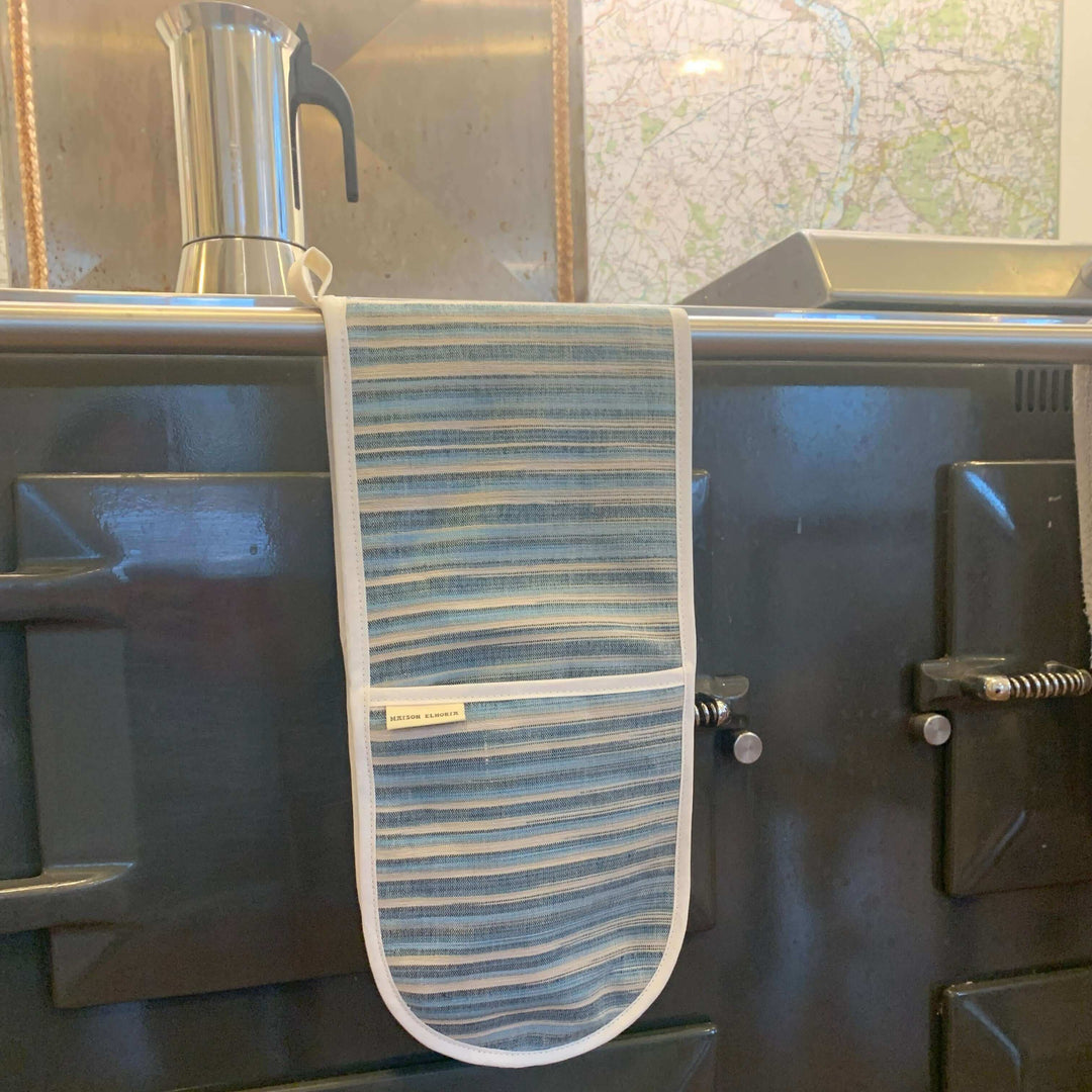 double oven glove with blue and sandy stripes Hanging over a range cooker front bar 