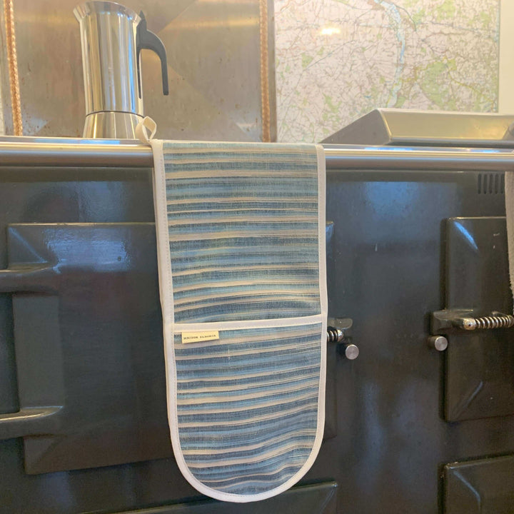 double oven glove with blue and sandy stripes Hanging over a range cooker front bar 