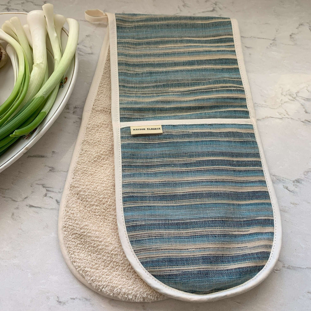Double oven glove blue striped on white grey  marble top with a dish of spring onions