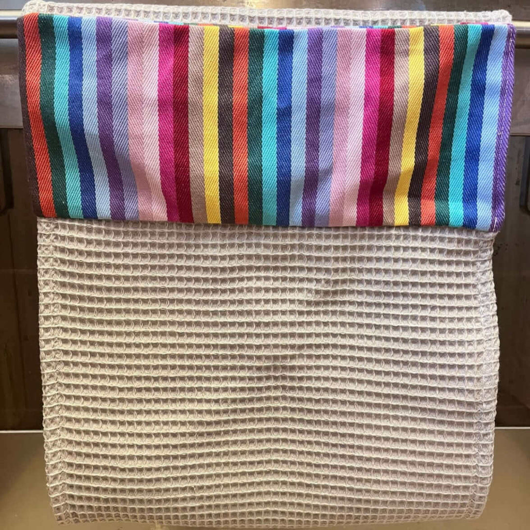 Roller towel beige cotton waffle gfabric with rainbow header hanging off a cooker