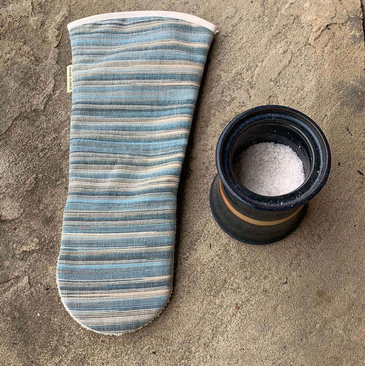  Blue striped long oven mitt gauntlet style flat with grey background showing the back of the glove with a pot of salt