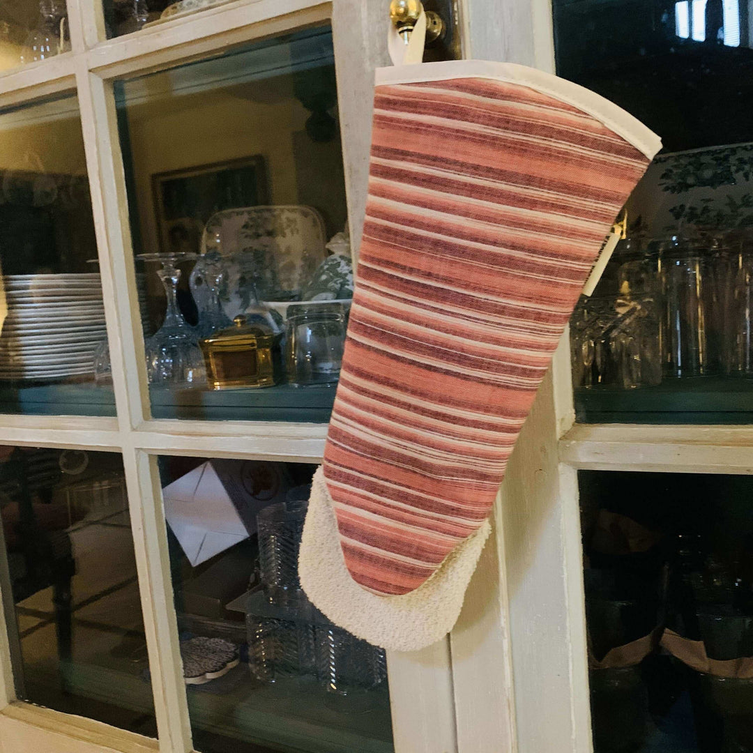 Oven glove gauntlet style long arm Red with off white heat resistant toweling Hanging off a kitchen cupboard door 