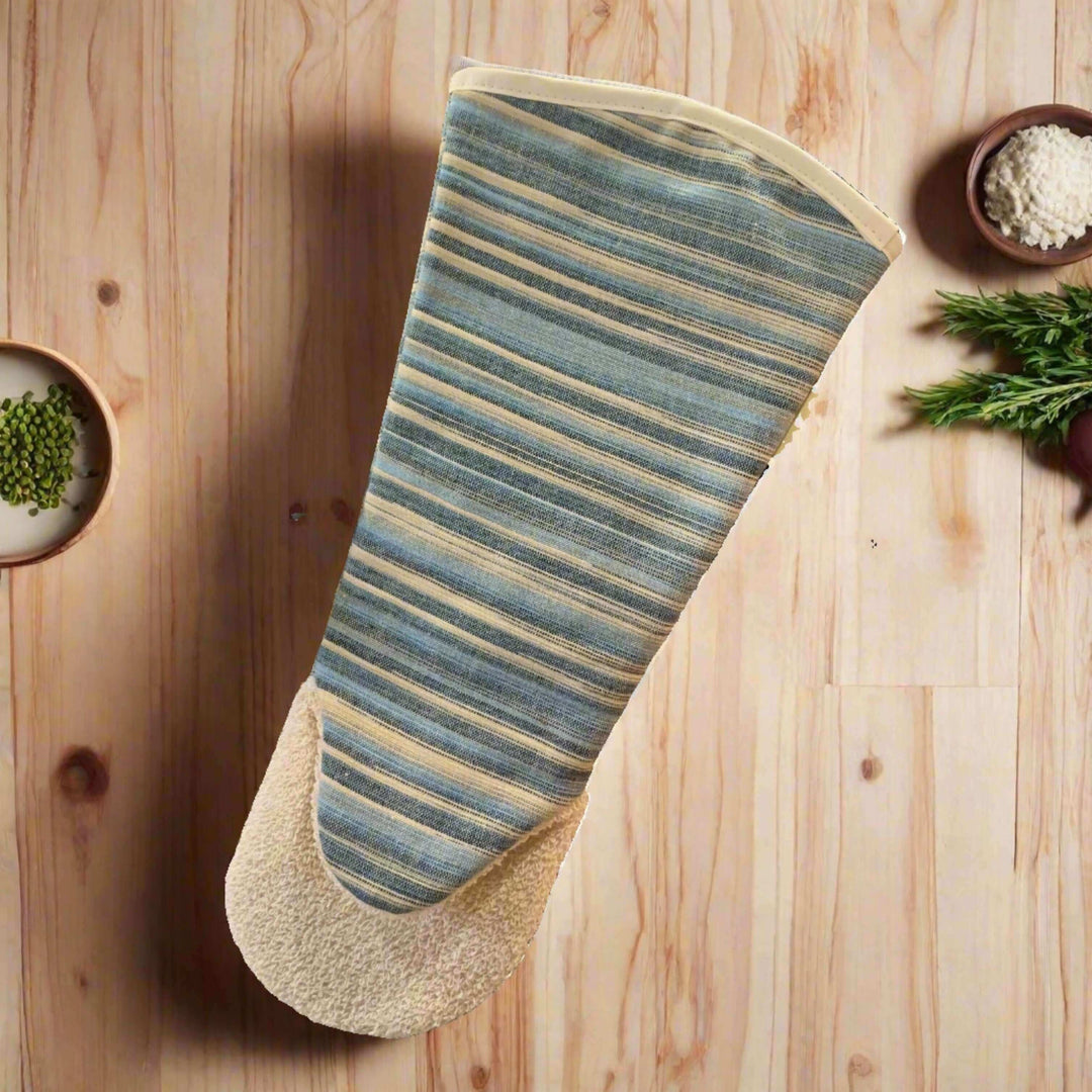 Blue striped long oven glove flat picture from the top on light wooden surface with spices and herbs around it