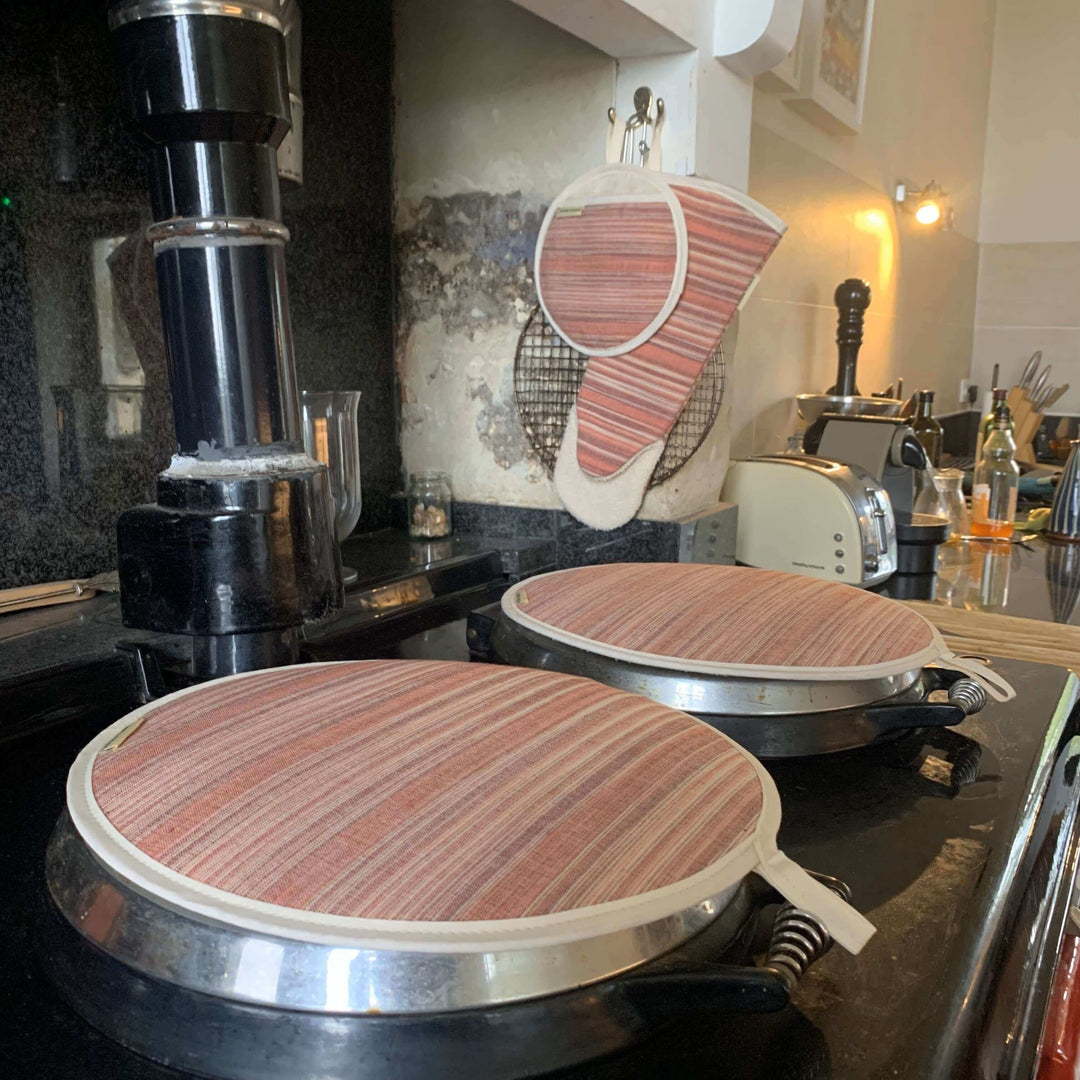 A pair of hob covers and oven gloves on the top of an Aga range cooker 