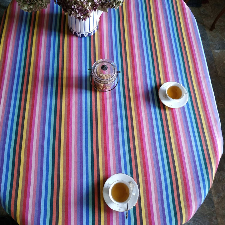 rainbow table cloth with a bouquet of dried flowers at the top, an antique see through sugar bowl and 2 cups of tea