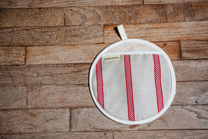 one oven glove pot holder type off white with red embroided stripes on wooden floor