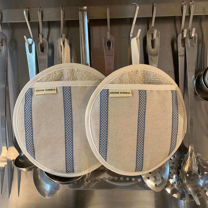 A pair of Pot holder round linen with blue stripes hanging with stainless steel kitchen cooking utensils 