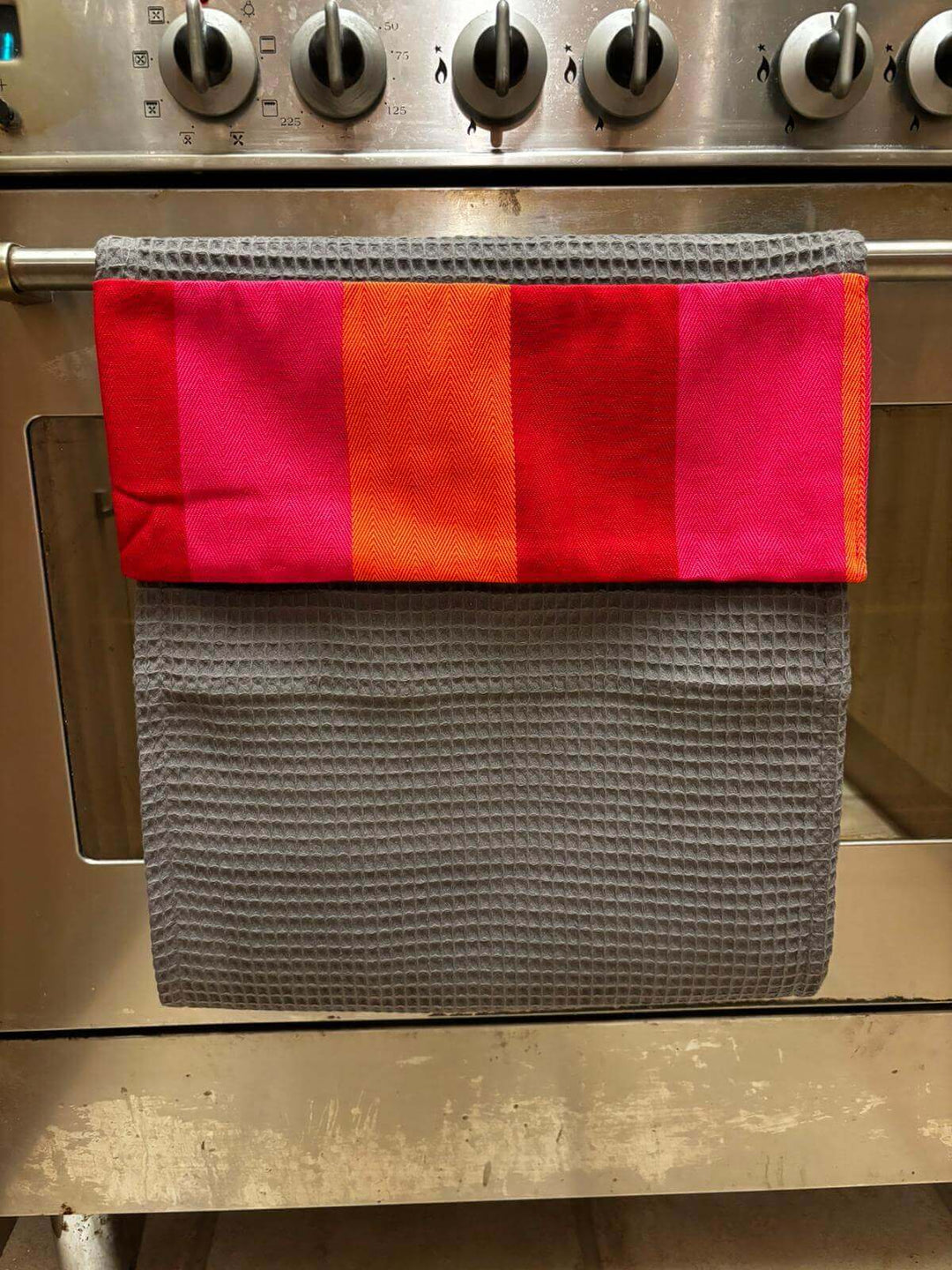  roller towel grey with red orange pink header hanging on the cooker kitchen rail 