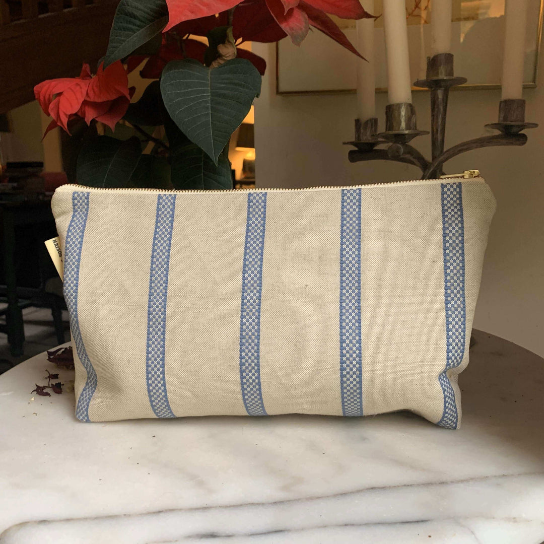 Blue Striped linen toiletry bag with plants behind it