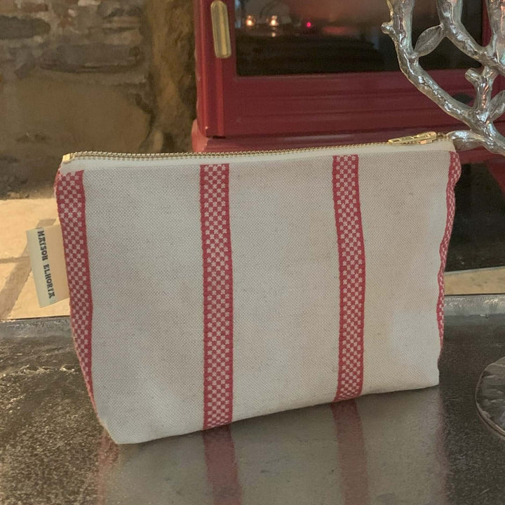 Makeup bag linen union with red stripes with a red wood burner in the background