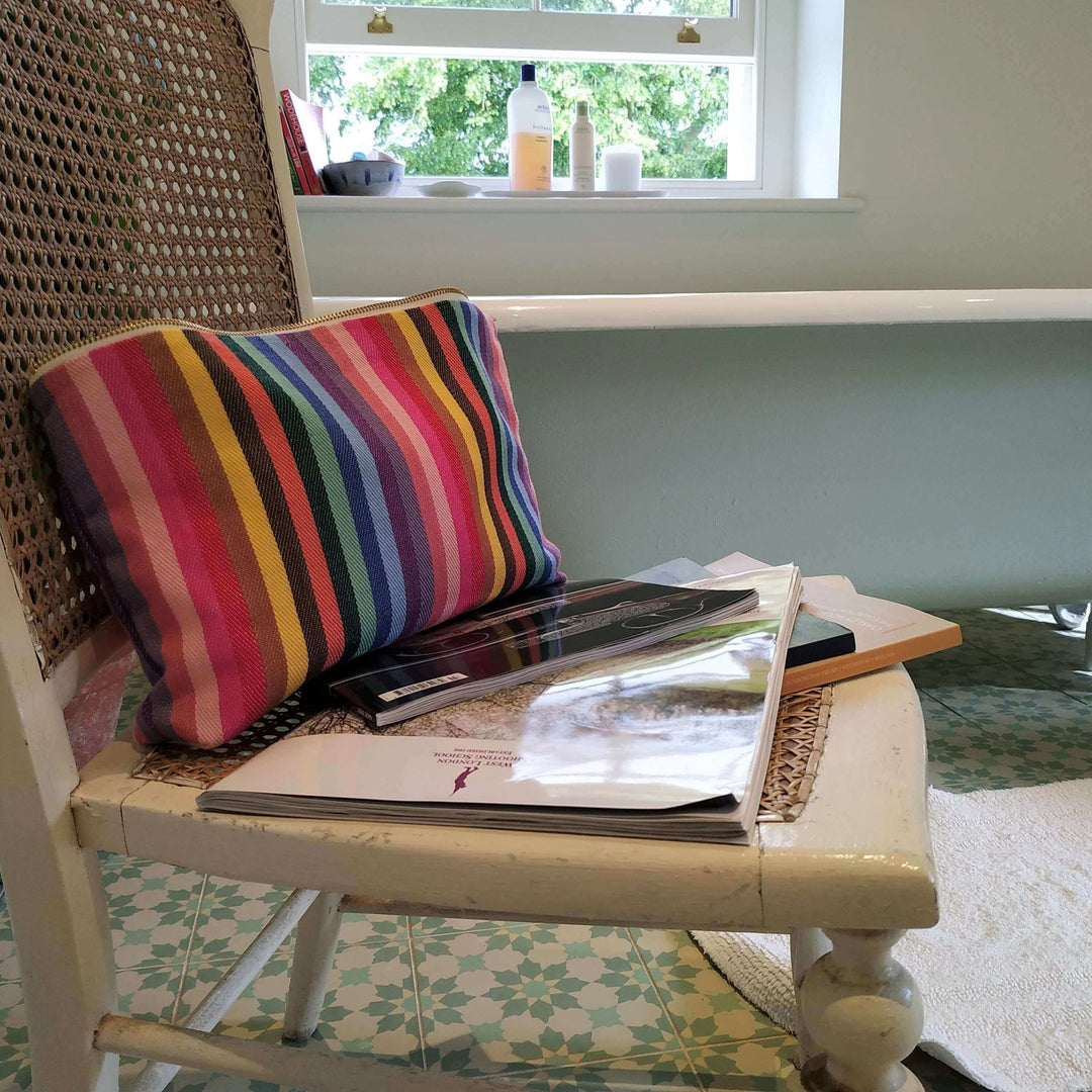 rainbow wash bag on a chair in a bathroom with a window in the background