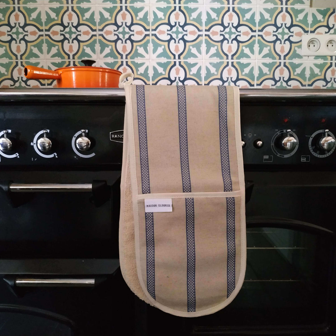 Premium linen union double oven gloves hanging over the front of a rangemaster cooker with a cast iron orange pot above it  and  tiled coloured background at the top