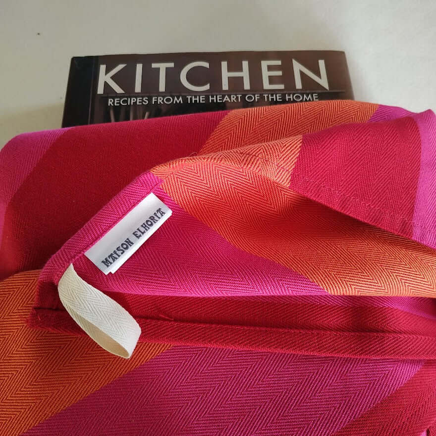 Red orange pink striped tea towel folded over a recipe book