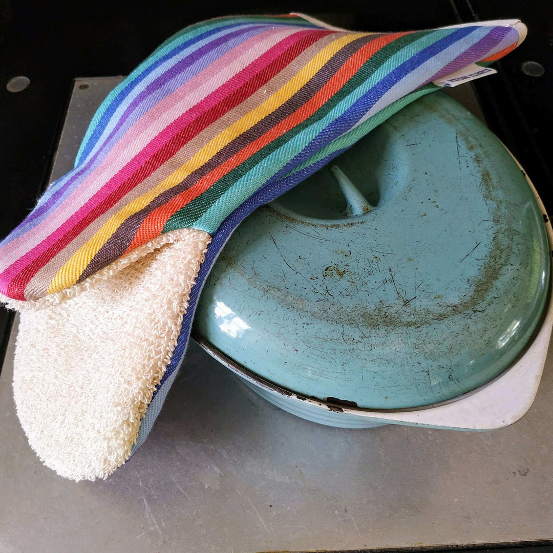 Rainbow long oven mitts snapper gauntlet over a cast iron turquoise oven dish on an Aga hot plate 