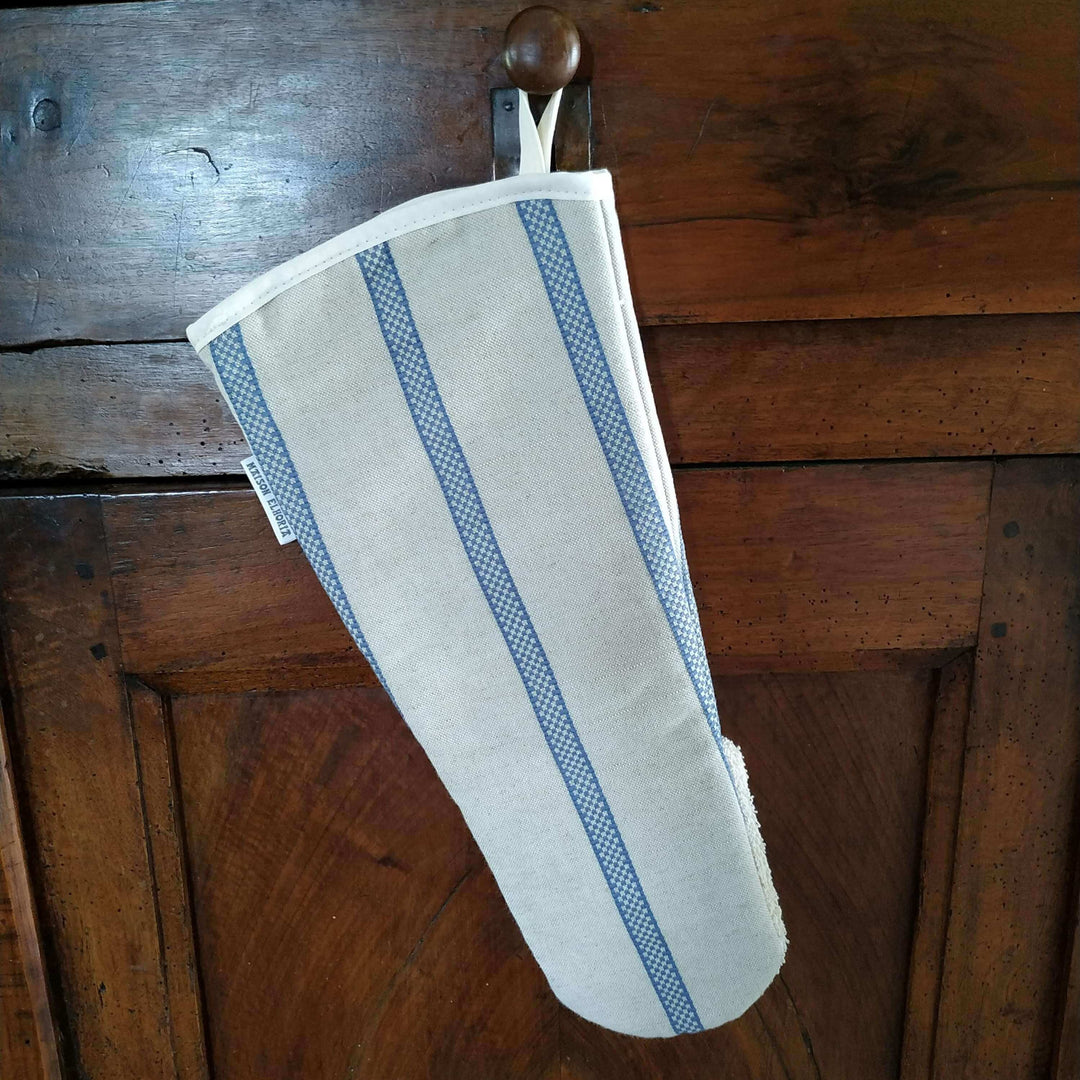 Linen union snapper gauntlet long oven glove with blue stripe hanging off the draw of a wooden cabinet