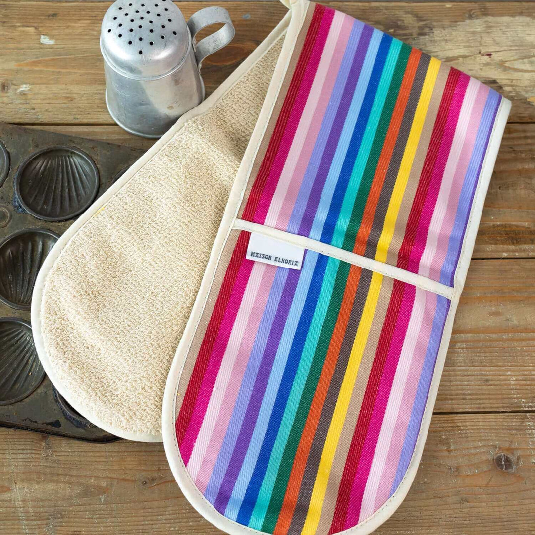 Premium organic cotton double oven gloves with rainbow stripes on wooden table with baking accessories