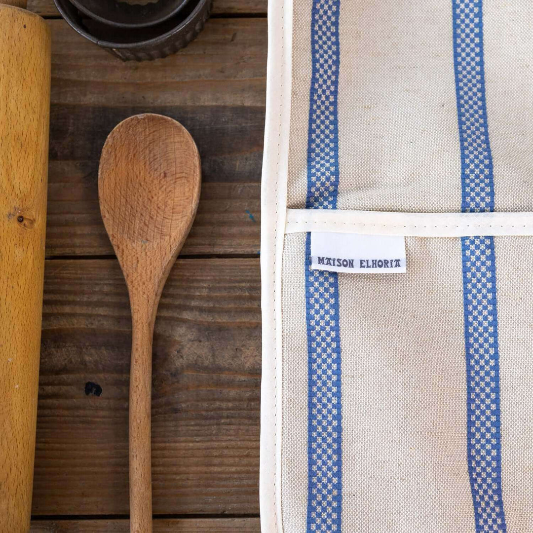 Premium linen union double oven gloves with blue stripes on wooden table with baking accessories  close up cut section
