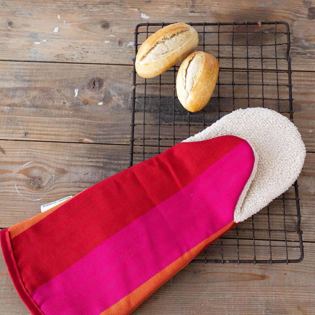 Gauntlet long oven glove red orange pink organic cotton with breads on a wooden table